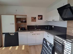 a kitchen with white cabinets and a sink and a table at Ferienwohnung im Ries in Wallerstein