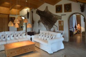 a living room with white couches and a zebra sculpture at Fewo Eitermoser Afrikanischer Traum in Pfaffing +33 photos
