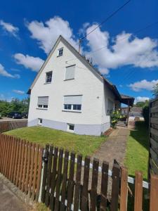a white house behind a wooden fence at Ferienwohnung im Ries in Wallerstein