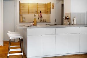 a white kitchen with a counter and a stool at Ruhbauernhof in Kirchzarten +98 photos