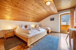 a bedroom with two beds and a wooden ceiling at Manuel's App Watschinger - Enzian in Sesto