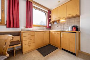 a small kitchen with wooden cabinets and a window at Manuel's App Watschinger - Enzian in Sesto +8 photos