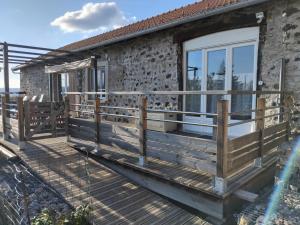 a house with a wooden deck next to a building at Gîte du Bachat in Vorey