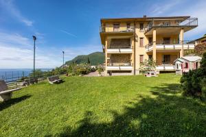 a large building with a grassy yard next to the ocean at Appartamento Alexander in Tignale
