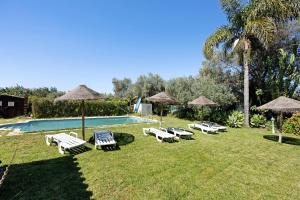 a group of lawn chairs and umbrellas next to a swimming pool at Quinta da Amendoeira in Foz