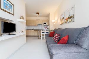 a living room with a gray couch and red pillows at El Sombrerito 4 in Caleta de Sebo