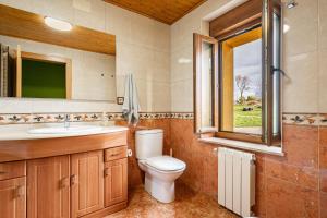 a bathroom with a toilet and a sink and a window at Casa Nueva in Salas +22 photos