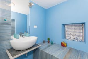 a bathroom with a white sink and a blue wall at Domus Elisae - Taormina in Taormina +18 photos