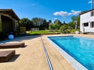 a swimming pool with benches next to a house at La Cour de la Forêt in Saint-Mars-de-Coutais