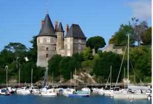 a castle on a hill with boats in the water at La Cour de la Forêt in Saint-Mars-de-Coutais