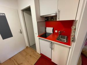 a small kitchen with a sink and a red wall at Ferienwohnung Inzell mit Bergblick in Inzell