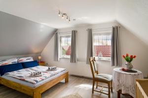 a bedroom with a bed and a chair and two windows at Huus Karoline in Junkersrott