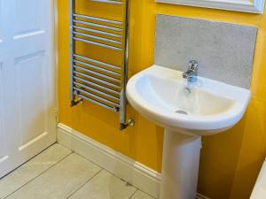 a bathroom with a white sink in a yellow wall at Corvette in Trearddur +14 photos