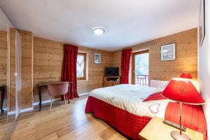 a bedroom with wooden walls and a bed and a desk at La source in Brides-les-Bains