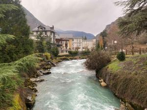 a river in front of a town with buildings at La source in Brides-les-Bains