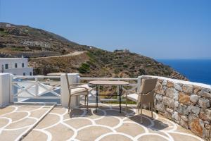 a patio with a table and chairs on a wall at Antiparos - Sikinos Sunset in Sikinos +16 photos