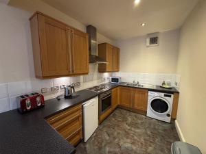 a kitchen with wooden cabinets and a washer and dryer at Cardiff City Escapes in Cardiff