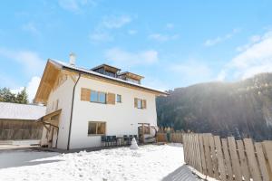 a house in the snow with a fence at Töniglerhof Apt Abendrot in Trodena