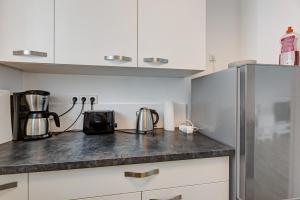a kitchen with white cabinets and a stainless steel refrigerator at Ferienwohnung Pepe in Donaueschingen