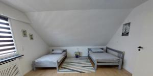 a attic room with two beds and a window at Ferienwohnung Sena in Weisweil