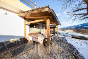 a wooden pergola with a bench on a patio at La pratolina monolocale in Castello di Fiemme