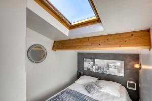a small bedroom with a bed and a skylight at Les Bois flottés in Poussan