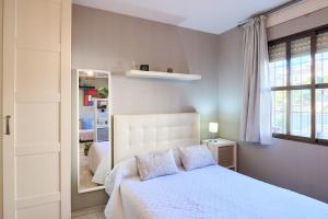 a bedroom with a white bed and a mirror at Casa Curro en Baena in Baena