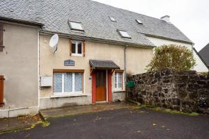 a house with a red door and a stone wall at Gite Tikilou 6 Pers proche montagne in La Tour-dʼAuvergne