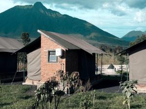 a building with a roof with mountains in the background at Volcanoes Over View Safaris & Camp in Nyarugina