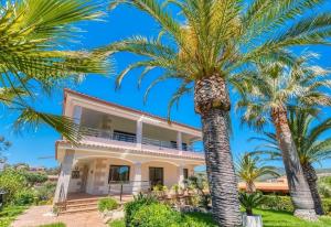 a house with palm trees in front of it at Costacabana - Villa Jaruco in Lloret de Mar