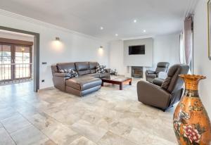 a living room with a couch and chairs and a tv at Costacabana - Villa Jaruco in Lloret de Mar