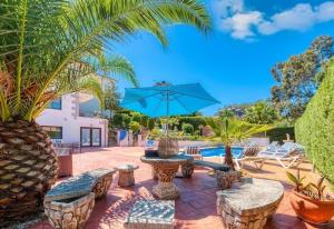 a patio with a fountain and chairs and a blue umbrella at Costacabana - Villa Jaruco in Lloret de Mar