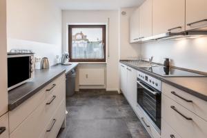 a large kitchen with white cabinets and a window at Heidis Dihei in Büsingen