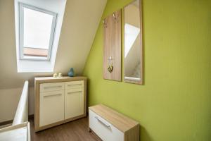 a bathroom with a green wall with a mirror and a drawer at Kleiner Priel in Dorum +15 photos