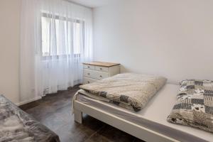 a white bedroom with a bed and a window at Heidis Dihei in Büsingen