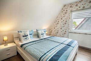 a bedroom with a bed with blue and white sheets and a window at Kleiner Priel in Dorum