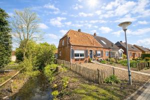a brick house with a fence next to a river at Huus ant Dörpsdiek in Krummhörn