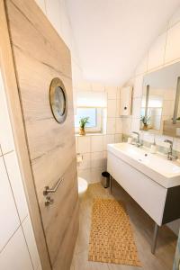 a bathroom with a sink and a toilet and a door at Huus ant Dörpsdiek in Krummhörn +28 photos