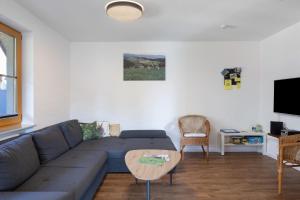 a living room with a blue couch and a table at Hinterbauernhof Fewo Kuhgeflüster in Stegen