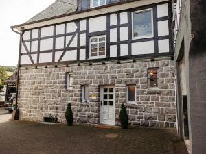 a stone building with a white door and windows at Ferienwohnung Wennetal in Schmallenberg