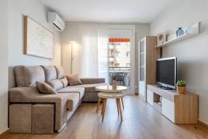 a living room with a couch and a tv at Apartamentos Cunidor - Cunit in Cunit