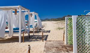 a beach with chairs and a canopy on the sand at Villa Mistral in Costa Rei