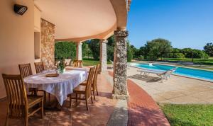 an outdoor dining area with a table and chairs and a swimming pool at Villa Mistral in Costa Rei