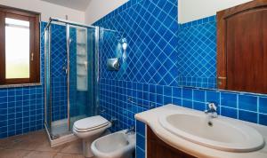 a blue tiled bathroom with a toilet and a sink at Villa Mistral in Costa Rei +22 photos