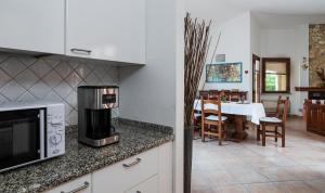 a kitchen with a microwave and a dining room at Villa Mistral in Costa Rei
