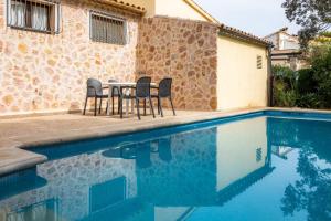 a patio with a table and chairs next to a swimming pool at Casa Isabel y Mateo in Cala de Sant Vicenc