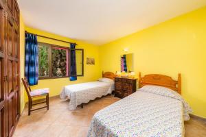 two beds in a room with yellow walls at Casa Isabel y Mateo in Cala de Sant Vicenc +20 photos