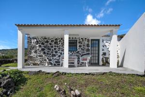 a stone house with a chair on a porch at Casa Ponta do Biscoito in Lajes do Pico