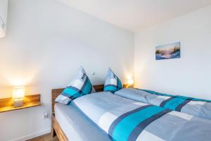 a bedroom with a bed with blue and white sheets at Gosewatt Wohnung 4 in Husby