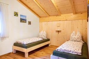 two beds in a room with wooden walls at Mittnackerhof Apartment Melisse in Sarntal